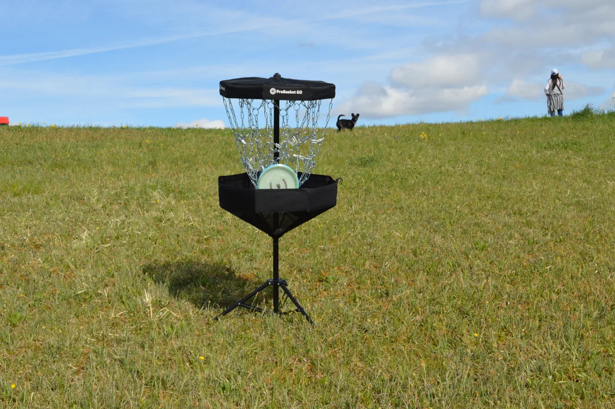 Ein türkisfarbener Frisbee fliegt in einen Fangkorb.